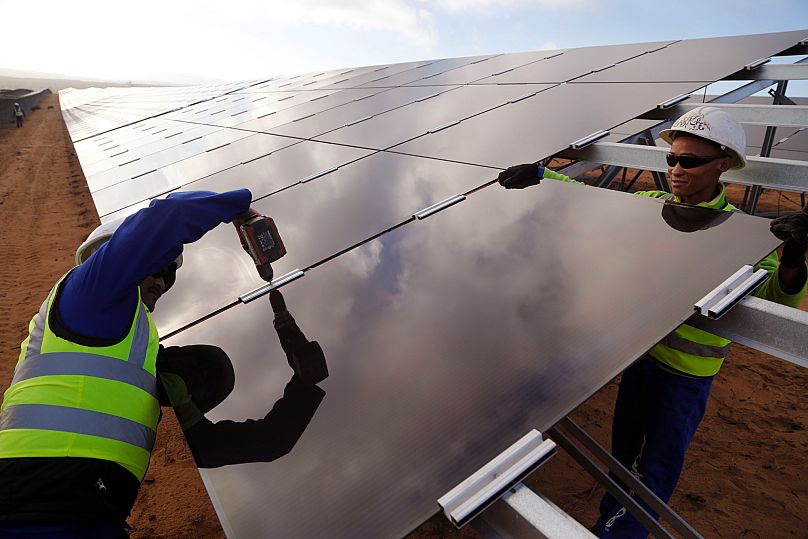 FILE - Workers install a solar panel at a photovoltaic solar park situated on the outskirts of the coastal town of Lamberts Bay, South Africa on March. 29, 2016.